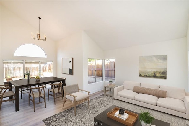 living room featuring light hardwood / wood-style flooring, high vaulted ceiling, and an inviting chandelier