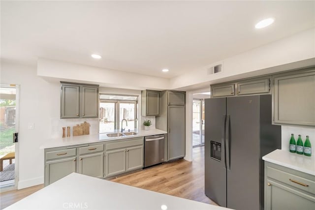 kitchen featuring light wood-type flooring, stainless steel appliances, plenty of natural light, and sink