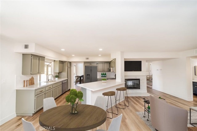 kitchen with a breakfast bar area, light hardwood / wood-style flooring, stainless steel appliances, and sink