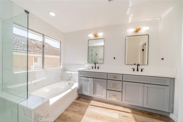 bathroom with a bathtub, vanity, and wood-type flooring