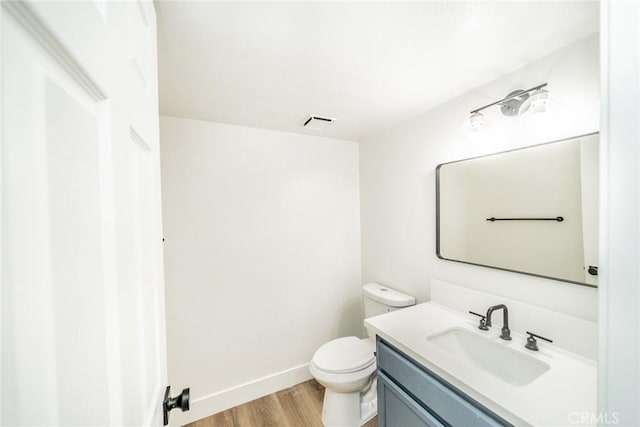 bathroom with wood-type flooring, vanity, and toilet