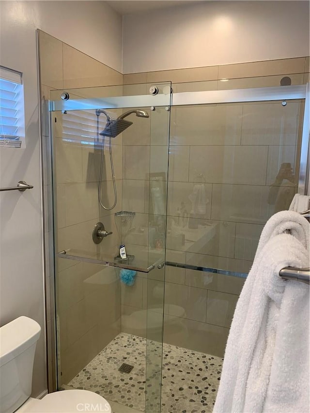 bathroom featuring toilet and a shower with shower door