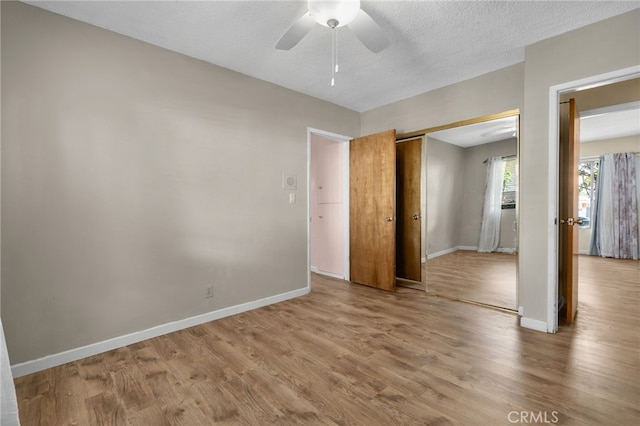 unfurnished bedroom featuring ceiling fan, light hardwood / wood-style floors, a textured ceiling, and a closet