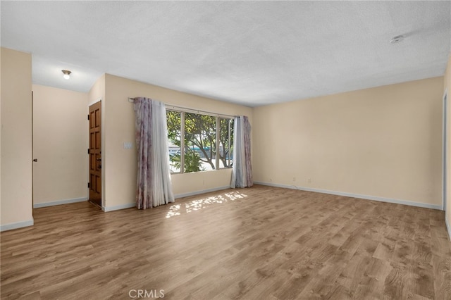 empty room featuring a textured ceiling and light wood-type flooring