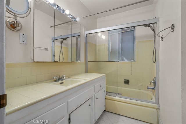 bathroom featuring tasteful backsplash, vanity, and bath / shower combo with glass door