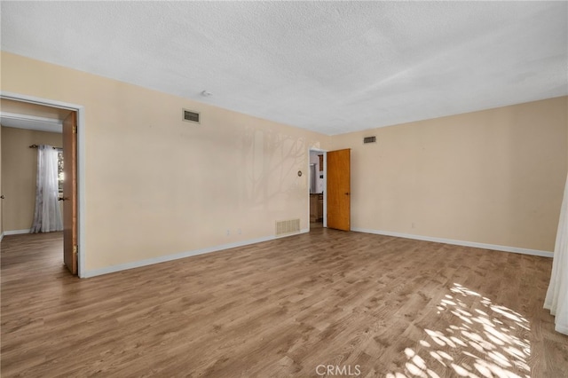 spare room with light hardwood / wood-style floors and a textured ceiling