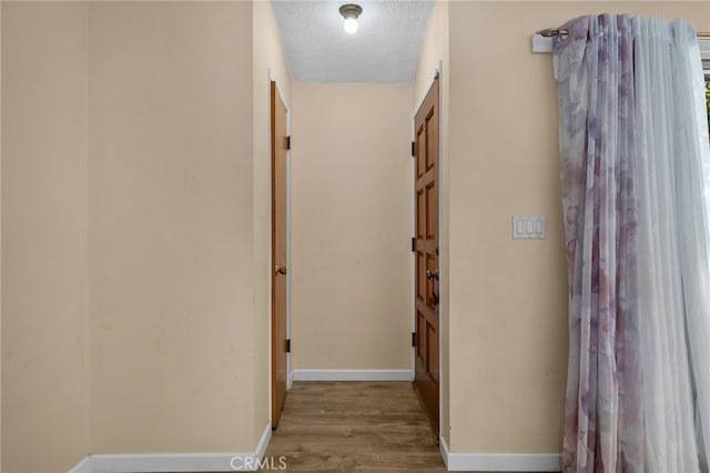 corridor with wood-type flooring and a textured ceiling