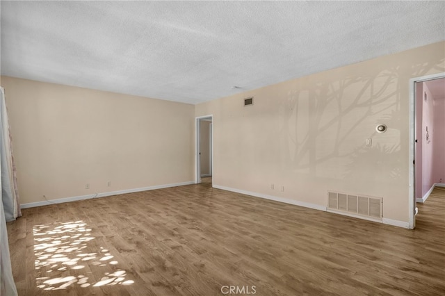 spare room with a textured ceiling and hardwood / wood-style flooring