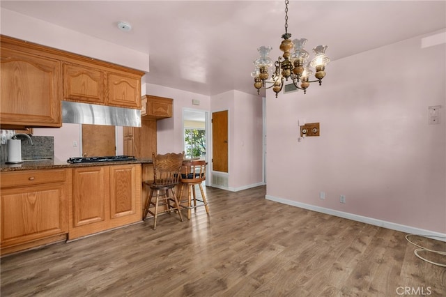 8653 Norwood Pl, Rosemead, CA 91770 - kitchen with a chandelier, a sink, under cabinet range hood, wood finished floors, and baseboards