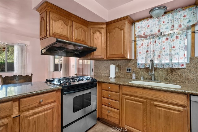 kitchen featuring sink, stainless steel appliances, tasteful backsplash, light stone counters, and light hardwood / wood-style flooring