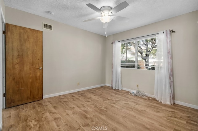 spare room with ceiling fan, light hardwood / wood-style floors, and a textured ceiling