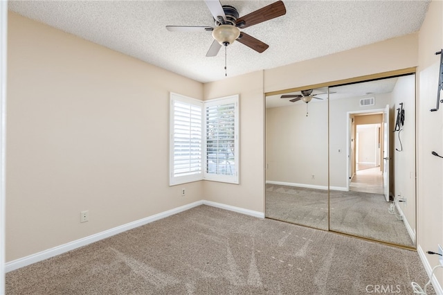 unfurnished bedroom featuring ceiling fan, a closet, a textured ceiling, and carpet flooring