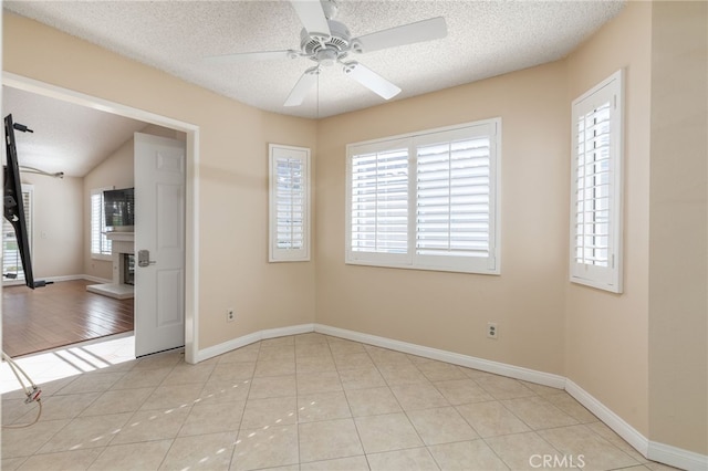 spare room with ceiling fan, light tile patterned floors, a textured ceiling, and lofted ceiling