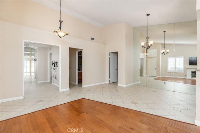 tiled spare room with vaulted ceiling and a chandelier