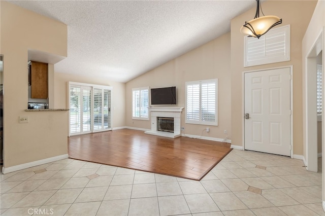 tiled entryway with a textured ceiling and vaulted ceiling