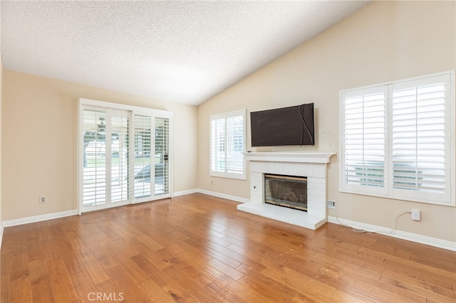 unfurnished living room with lofted ceiling, a healthy amount of sunlight, a fireplace, and hardwood / wood-style floors