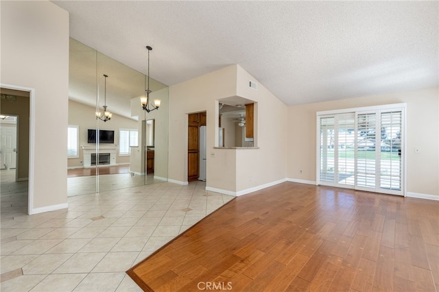 unfurnished living room featuring vaulted ceiling, an inviting chandelier, and light tile patterned flooring