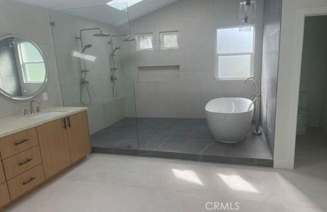 bathroom with vaulted ceiling with skylight, vanity, separate shower and tub, and tile patterned floors