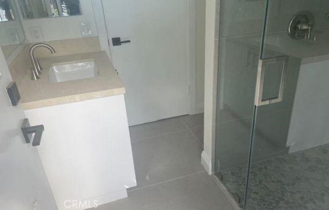 bathroom with tile patterned flooring, vanity, and a shower with door