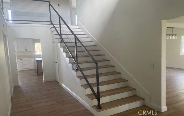 staircase with hardwood / wood-style floors and a chandelier