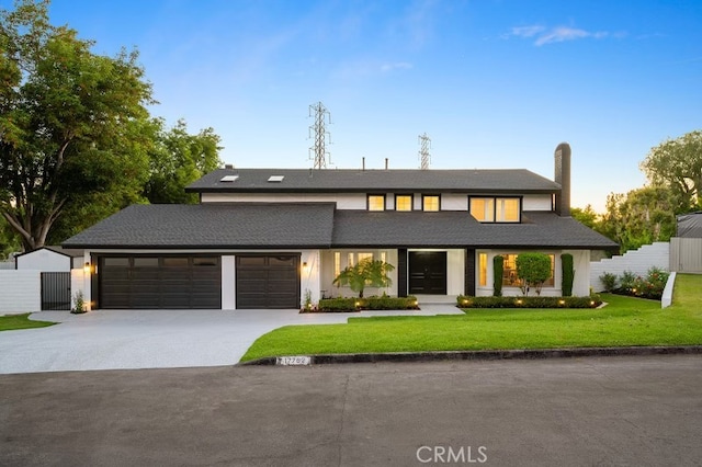 view of front of house featuring driveway, a front lawn, an attached garage, and fence