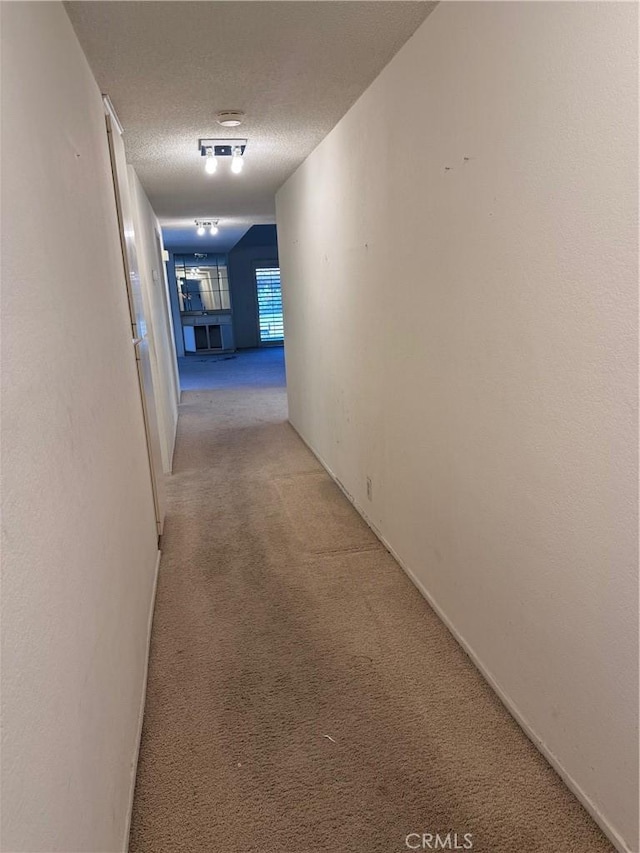 hall with light colored carpet and a textured ceiling