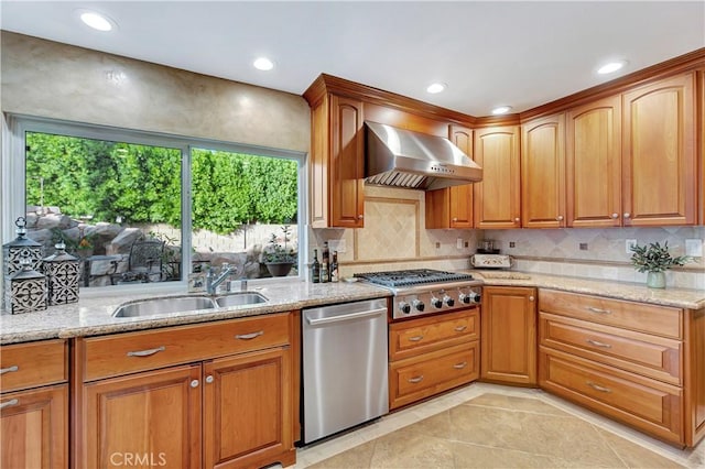 kitchen featuring light stone countertops, wall chimney exhaust hood, stainless steel appliances, sink, and light tile patterned floors