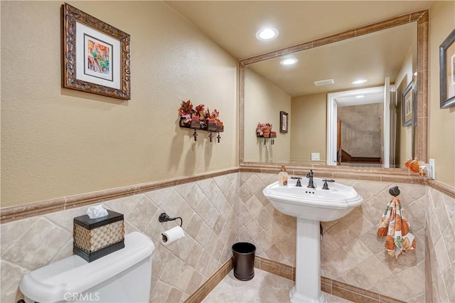 bathroom with tile walls and toilet