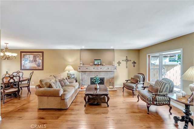 living room with a tile fireplace, light hardwood / wood-style floors, and a notable chandelier