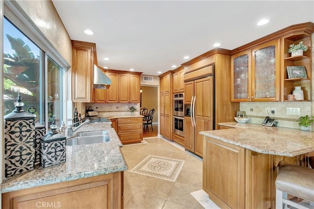 kitchen with sink, stainless steel appliances, tasteful backsplash, light stone counters, and kitchen peninsula