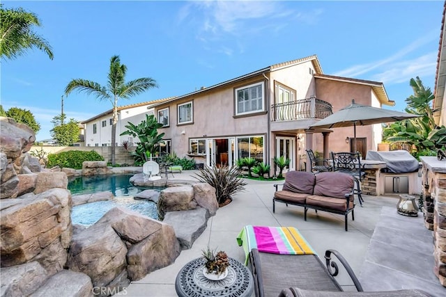 back of property with a balcony, exterior kitchen, and a patio