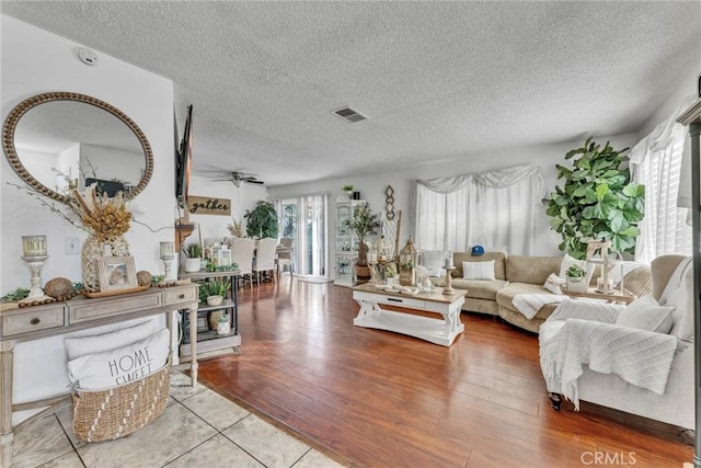 living room with ceiling fan, light hardwood / wood-style floors, and a textured ceiling