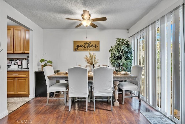 dining room with ceiling fan, a textured ceiling, and hardwood / wood-style flooring