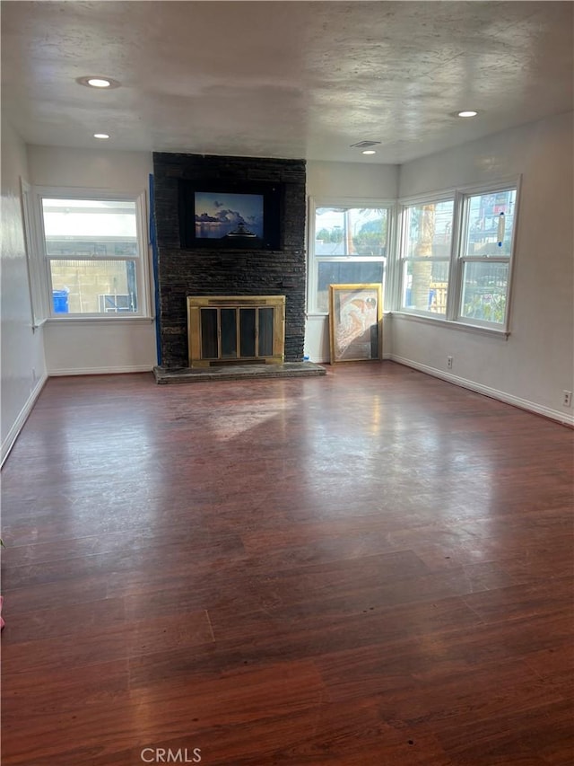 unfurnished living room featuring a textured ceiling, a fireplace, and dark hardwood / wood-style floors