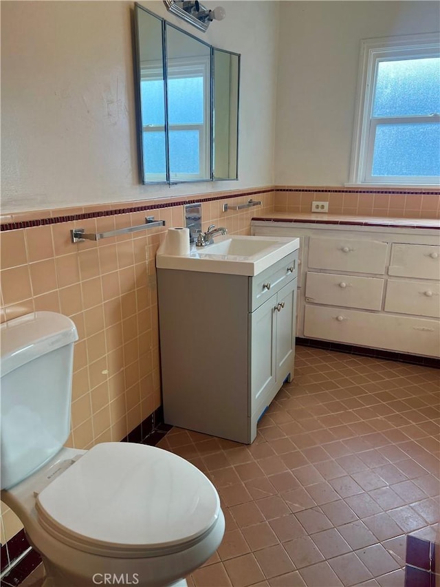 bathroom featuring tile patterned floors, vanity, tile walls, and toilet