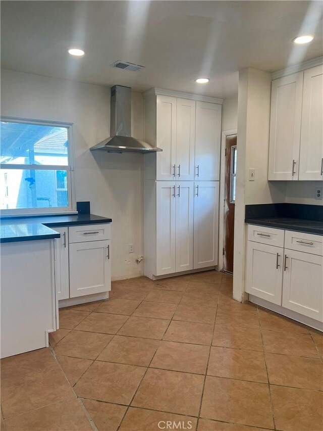 kitchen with white cabinets, wall chimney exhaust hood, and light tile patterned floors