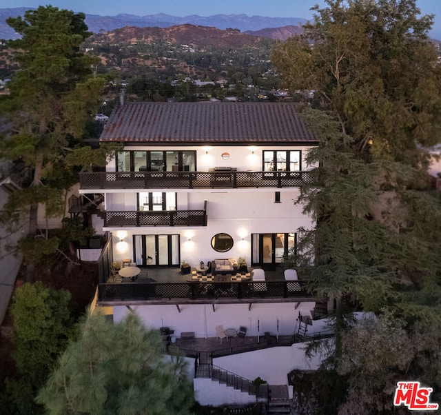 back of property featuring a mountain view, a patio area, and a balcony