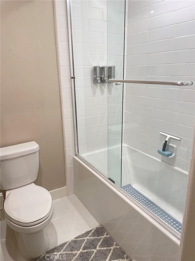 bathroom featuring tile patterned flooring, toilet, and shower / bath combination with glass door