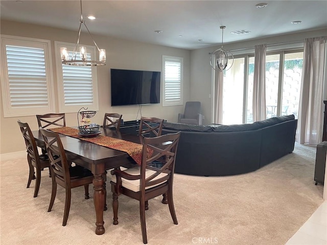 dining space featuring light carpet and an inviting chandelier