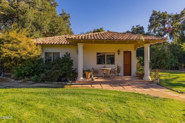 rear view of house featuring stucco siding, a tiled roof, a patio area, and a yard