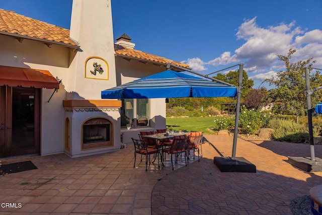 view of patio / terrace featuring exterior fireplace and outdoor dining area