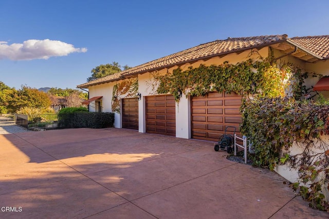 garage featuring fence and concrete driveway