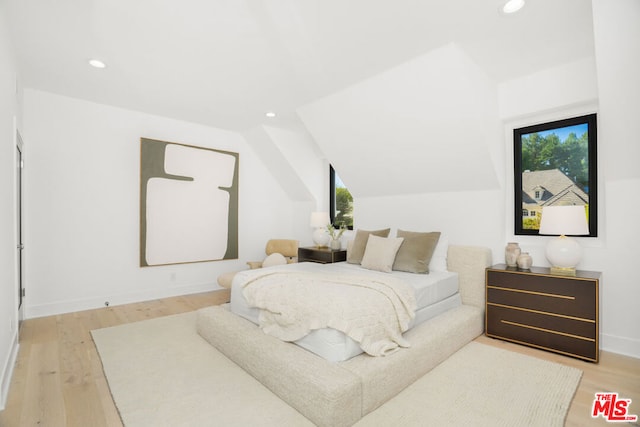 bedroom featuring multiple windows, light hardwood / wood-style flooring, and vaulted ceiling