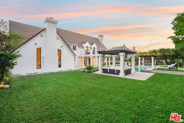 back house at dusk with a yard, a pergola, a balcony, and a patio