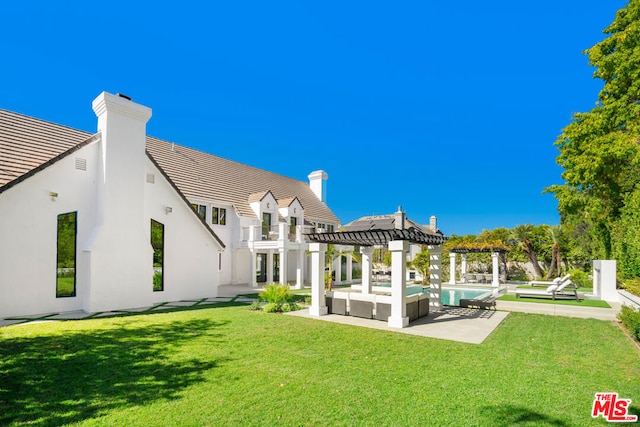 rear view of property featuring a pergola, a balcony, a patio, an outdoor living space, and a yard