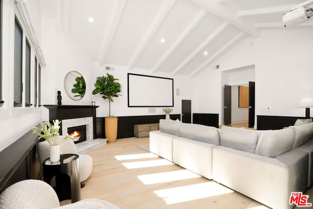 cinema room with beamed ceiling, light hardwood / wood-style floors, high vaulted ceiling, and a fireplace