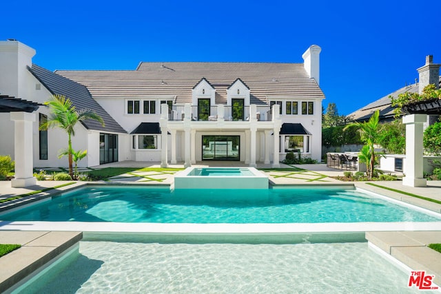 back of house with a pool with hot tub, a patio area, and a balcony