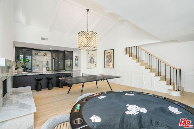 recreation room featuring beam ceiling, high vaulted ceiling, and light wood-type flooring