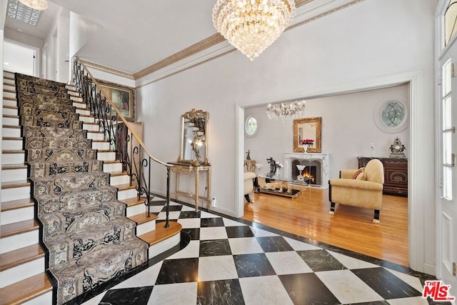 foyer featuring dark hardwood / wood-style floors, crown molding, a healthy amount of sunlight, and a notable chandelier