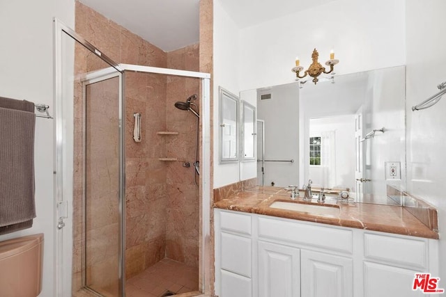 bathroom with a chandelier, vanity, toilet, and a shower with shower door